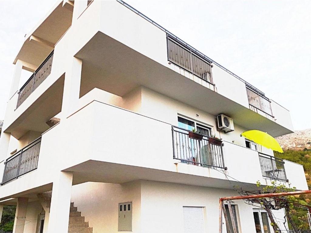 een wit gebouw met balkons en een gele paraplu bij Apartments with a parking space Podstrana, Split - 22374 in Podstrana