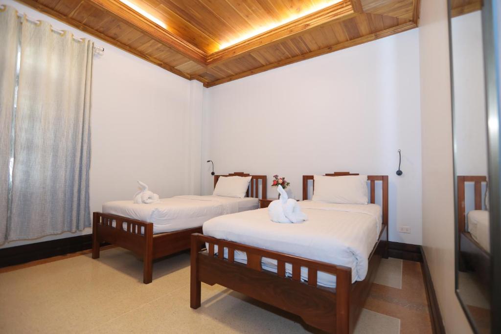 two beds in a room with white sheets at Villa KiengKham晶康民宿 in Luang Prabang