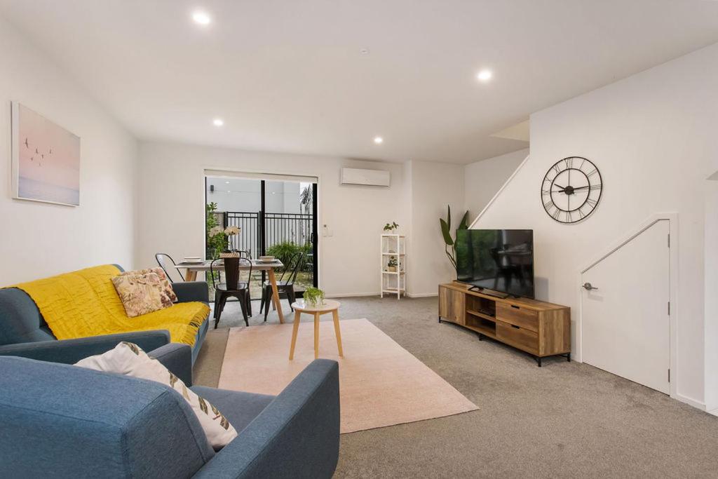 a living room with a blue couch and a tv at Light & Spacious 2Bdrm Townhouse Off Street Park in Christchurch