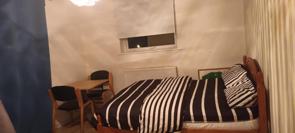 a bedroom with a bed and a table and a window at Croydon Homestay-Shared Apartment with Shared Bathroom in South Norwood