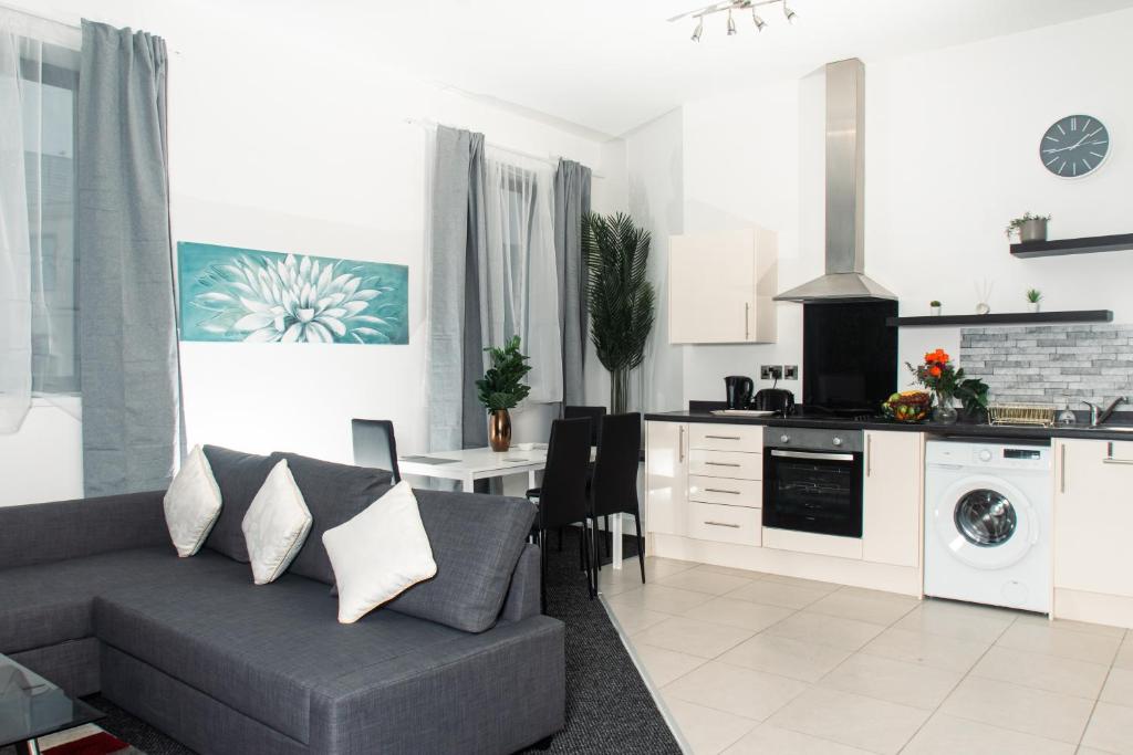 a living room with a couch and a kitchen at Modern and Spacious 2 bedroom Apartment, Close to Stadiums, Transport links, Free Parking in Manchester