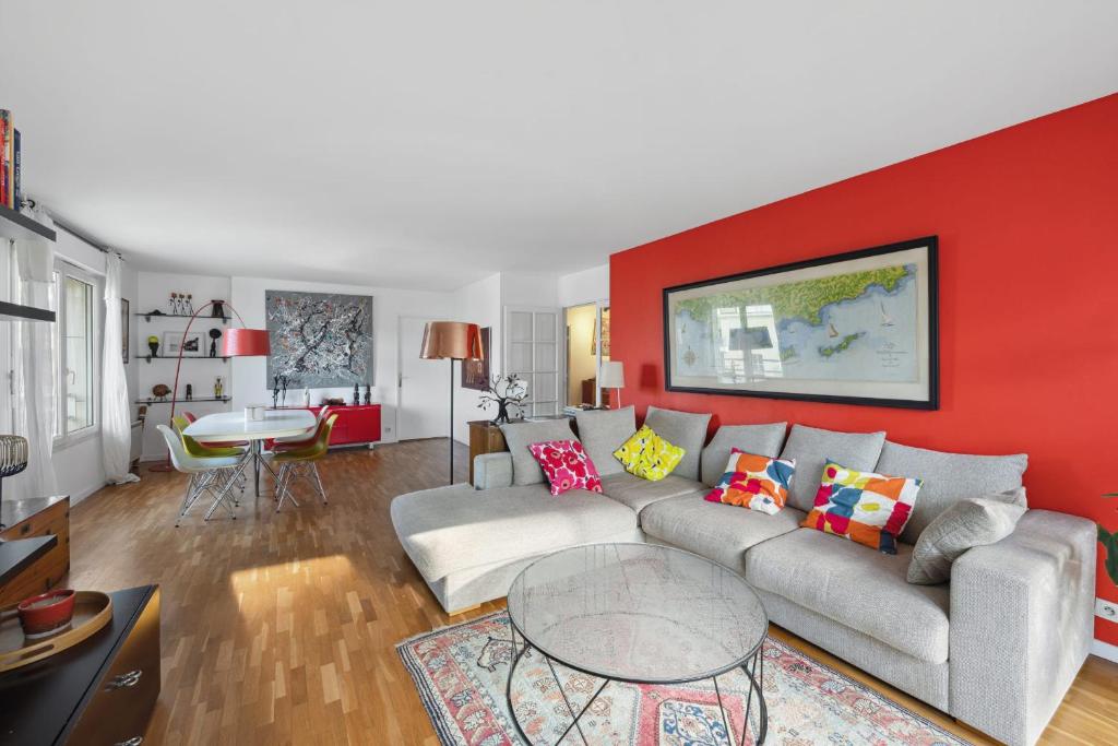 uma sala de estar com um sofá e uma parede vermelha em Large bright T4 in Issy-les-Moulineaux - Welkeys em Issy-les-Moulineaux