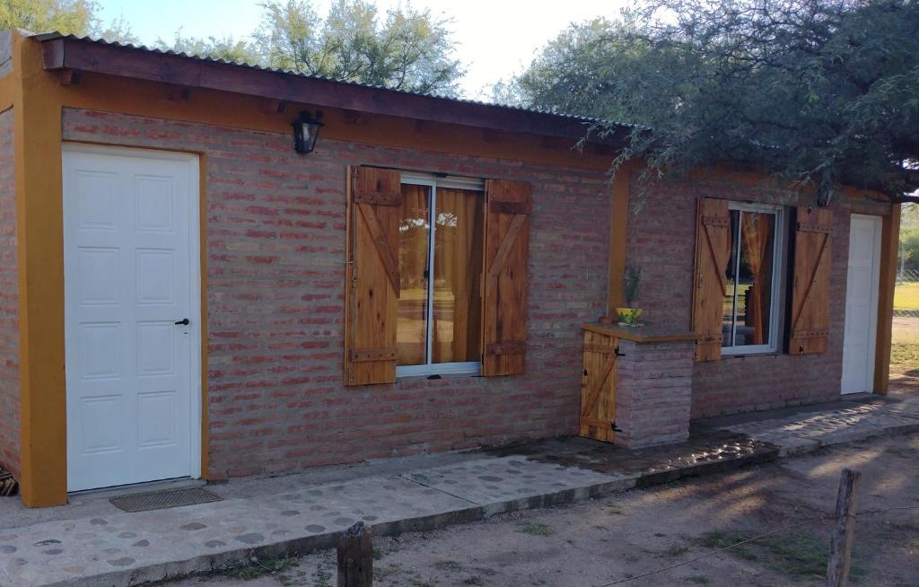 un edificio de ladrillo con una puerta y ventanas blancas en Cabañas La Peperina 2 in 