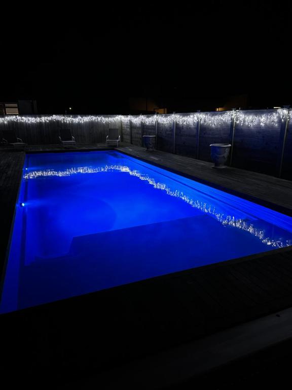 a swimming pool with blue illumination at night at Hobbiton Pool House in Matamata