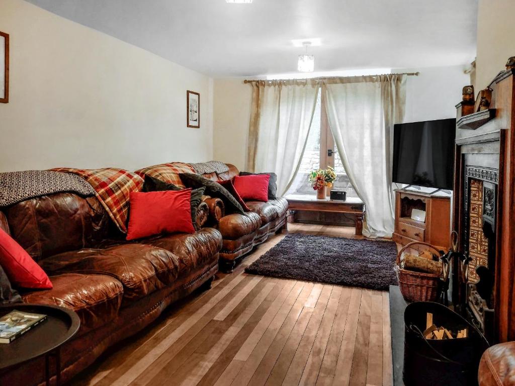 a living room with a brown leather couch and a television at Grange Court in Cliburn
