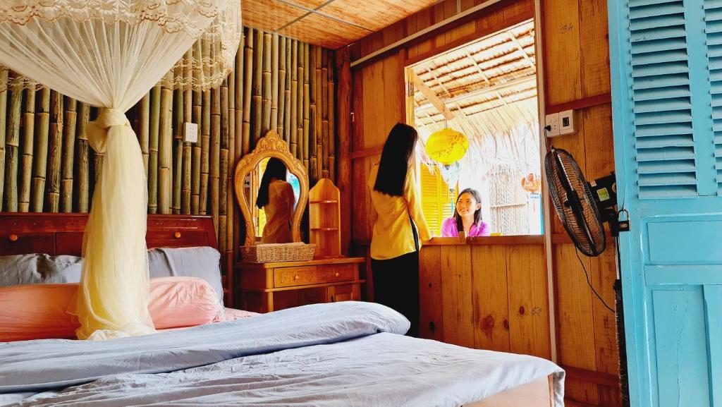 Schlafzimmer mit einem Bett, einem Fenster und einem Spiegel in der Unterkunft homestay 9 sông 