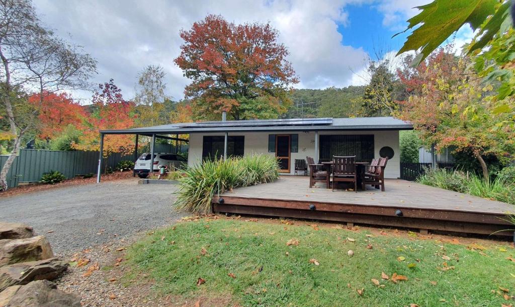 a house with a deck with a table and chairs at Crystalbrook Cottage in Porepunkah