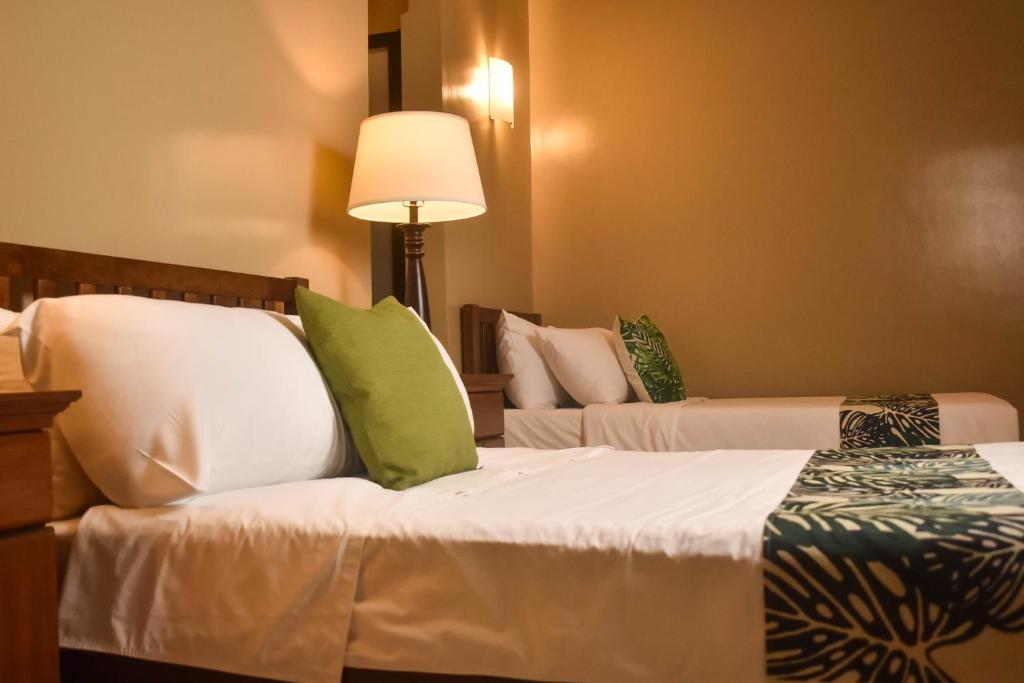 Stay Inn Plus في Mexico: غرفة فندقية بسريرين مع مخدات خضراء وبيضاء