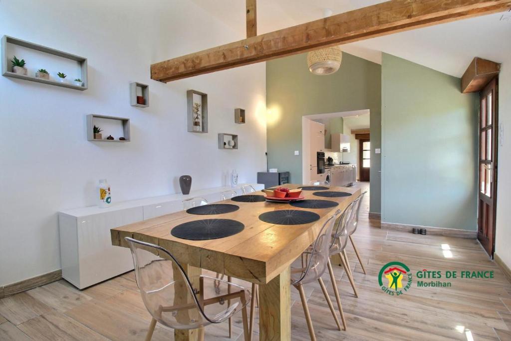a large dining room with a wooden table and chairs at La grée des dinosaures in Saint-Gravé