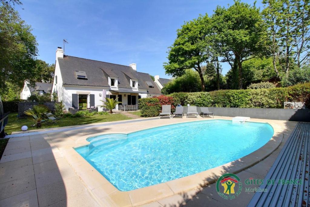 a swimming pool in front of a house at Villa mimosas in Brech