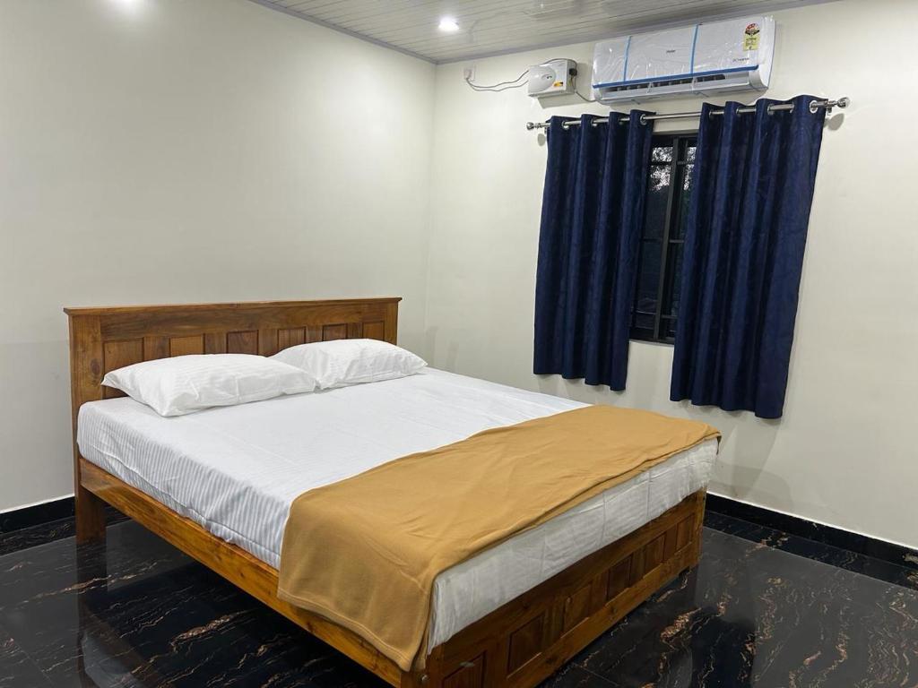 a bedroom with a large bed with blue curtains at Yashovana Nature Stay Gokarna in Gokarna