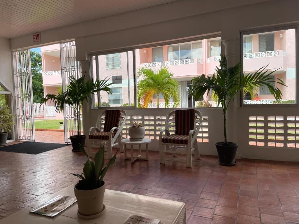 a room with a table and chairs and palm trees at The Monteray Hotel in Christ Church