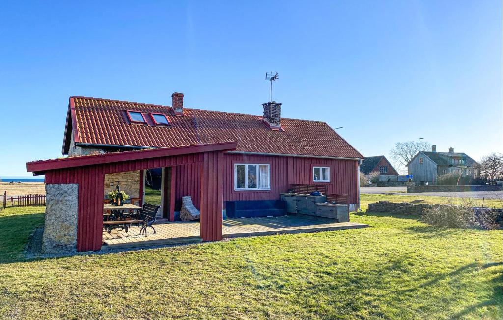 3 Bedroom Stunning Home In Degerhamn في Degerhamn: منزل احمر صغير مع سطح خشبي