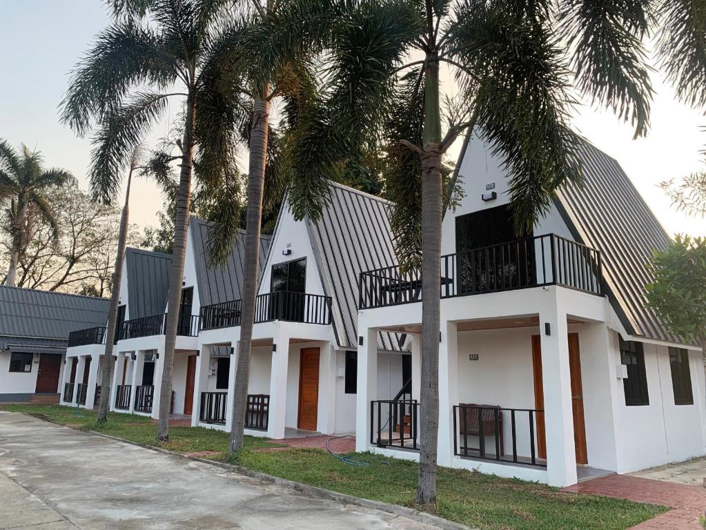 a building with palm trees in front of it at Rainbow House Resort in Kamphaeng Phet