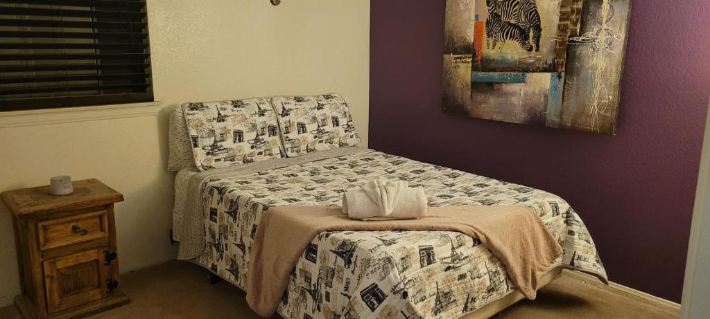 a bedroom with a bed and a table and a painting at Be our Guest - Shared Home Lancaster in Palmdale