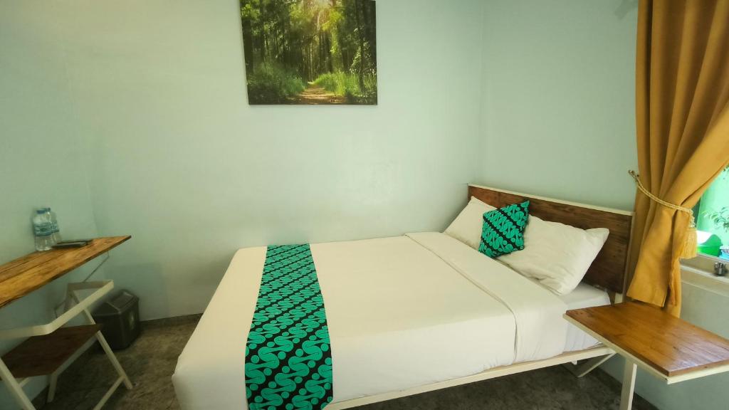 um pequeno quarto com uma cama e uma mesa em Kalimaya Residence Syariah 1 by Cocotel em Brumbung