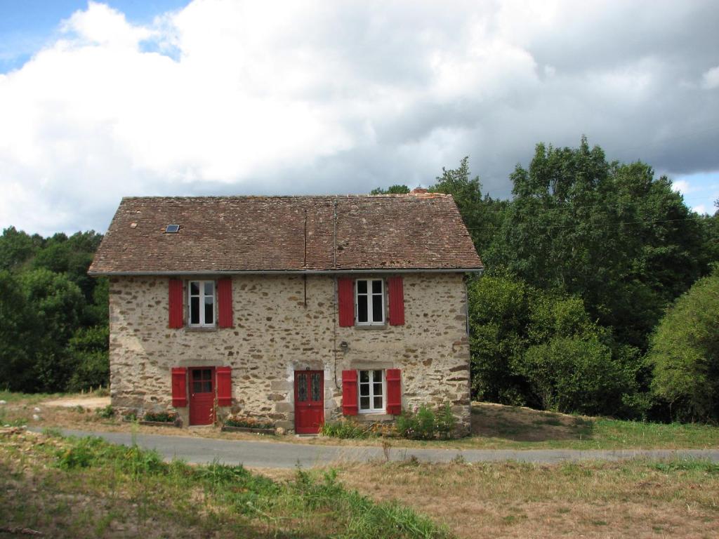 une ancienne maison en pierre avec des portes rouges sur un champ dans l'établissement Tavaud, à Dournazac