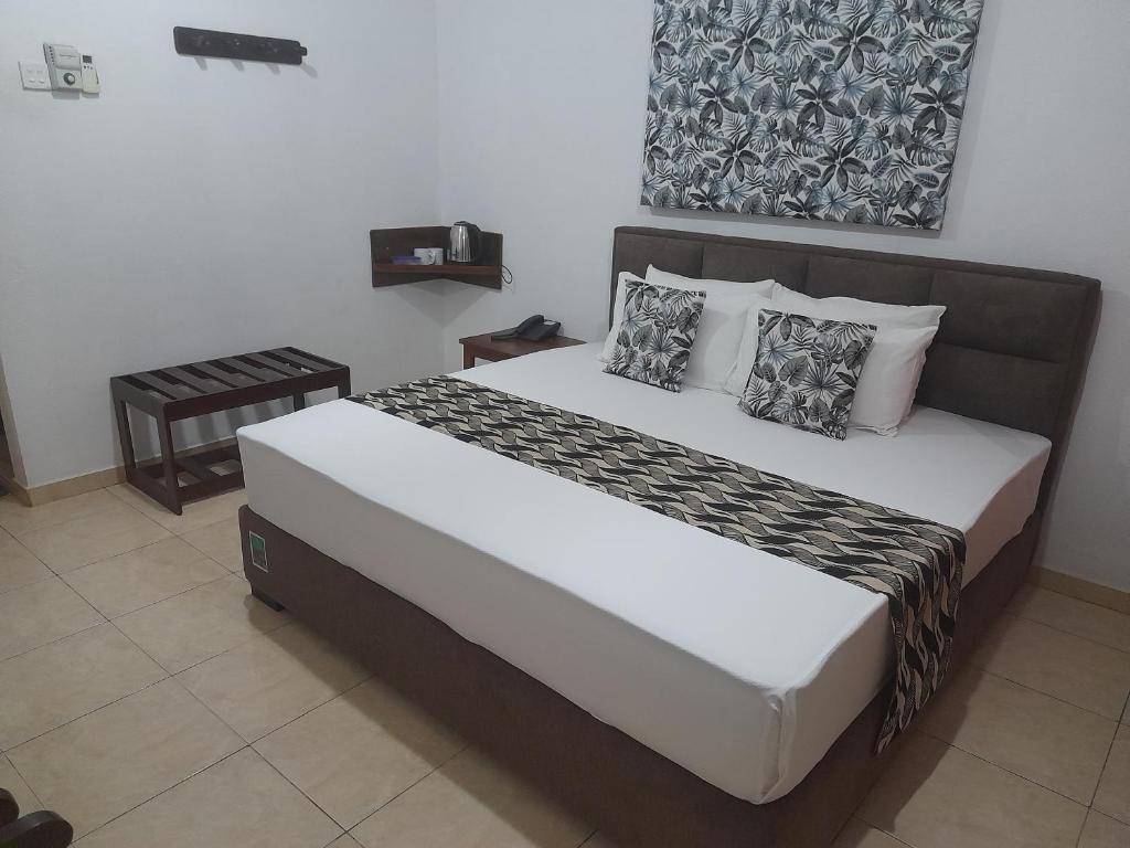 a bedroom with a large bed with pillows at Larn's Villa Hotel & Apartment in Wadduwa