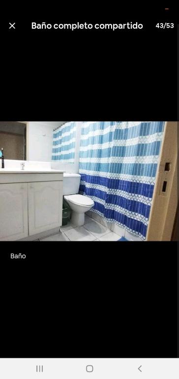 a bathroom with a sink and a toilet and a blue shower curtain at Habitaciones en las condes, Cercano a metro in Santiago