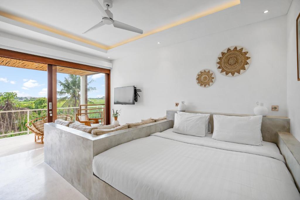 a bedroom with a large bed and a couch at Pagi Villas by Hombali in Mengwi