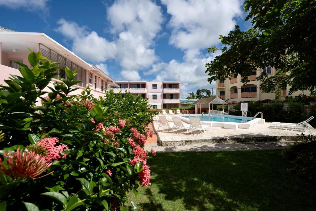 a building with a yard with a swimming pool and flowers at The Monteray Hotel in Christ Church