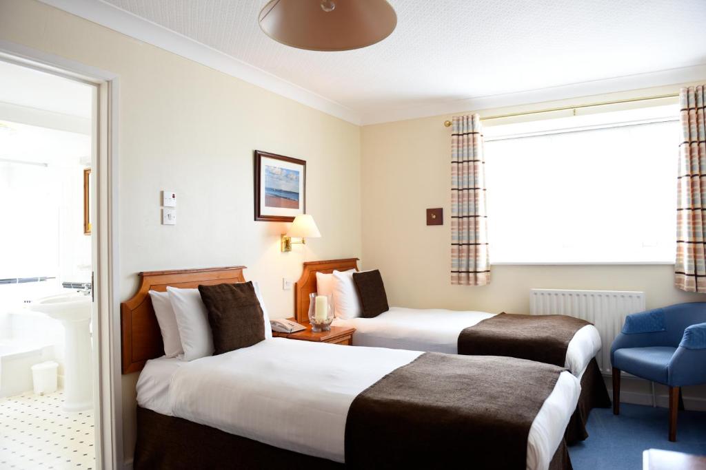 a hotel room with two beds and a chair at The Riviera Hotel & Apartments - Alum Chine in Bournemouth