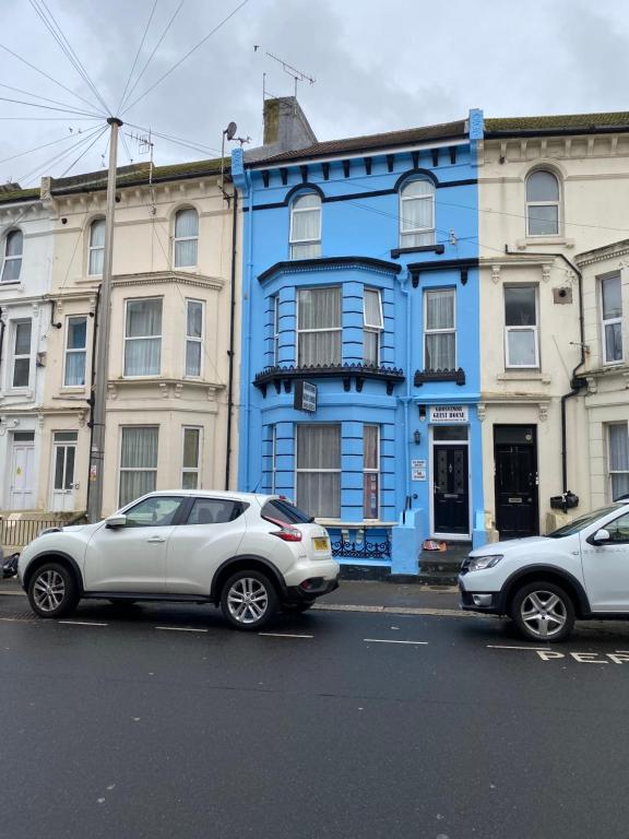 two cars parked in front of a blue building at Grosvenor Guest House in Hastings