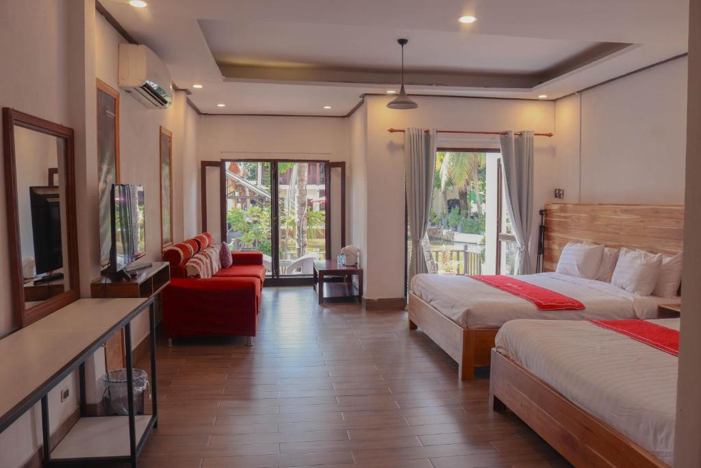 a hotel room with two beds and a television at Luang Prabang Villa Oasis in Luang Prabang
