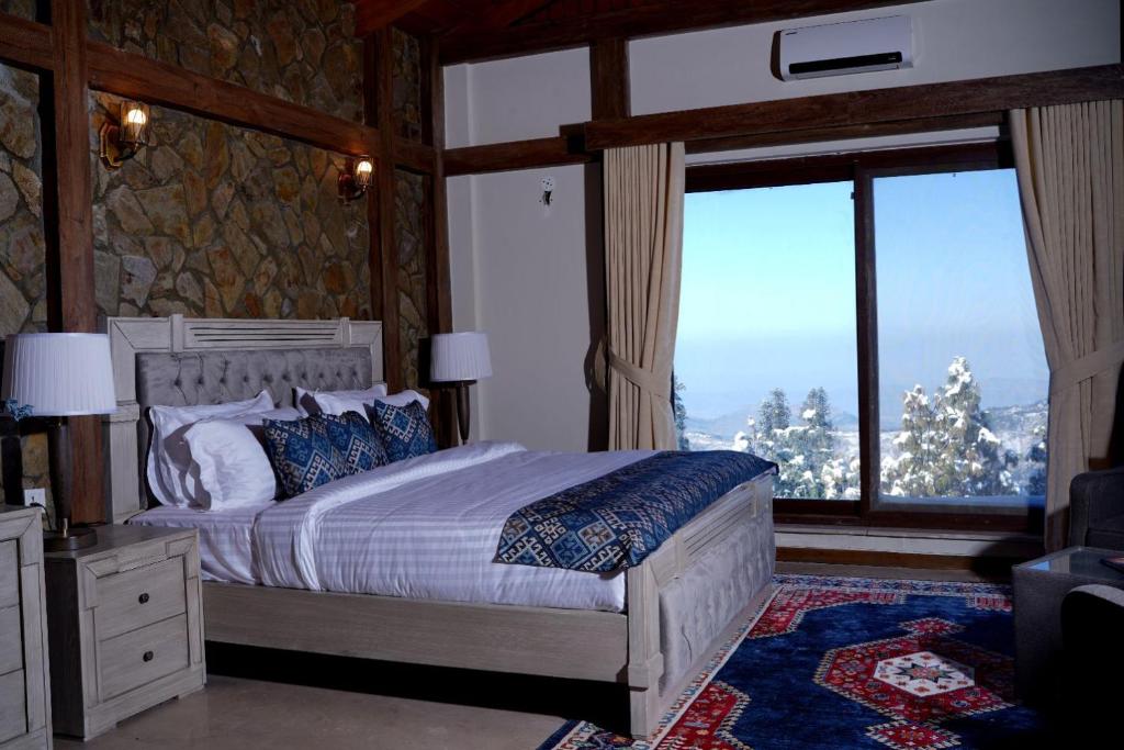een slaapkamer met een bed en een groot raam bij Cedar Lodges Resort and Residences Galiyat in Chhāngla Gali