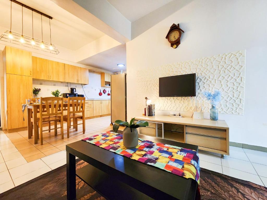 cocina y sala de estar con mesa y TV. en Klang Prima Bayu Cozy 4-Room Retreat, en Klang