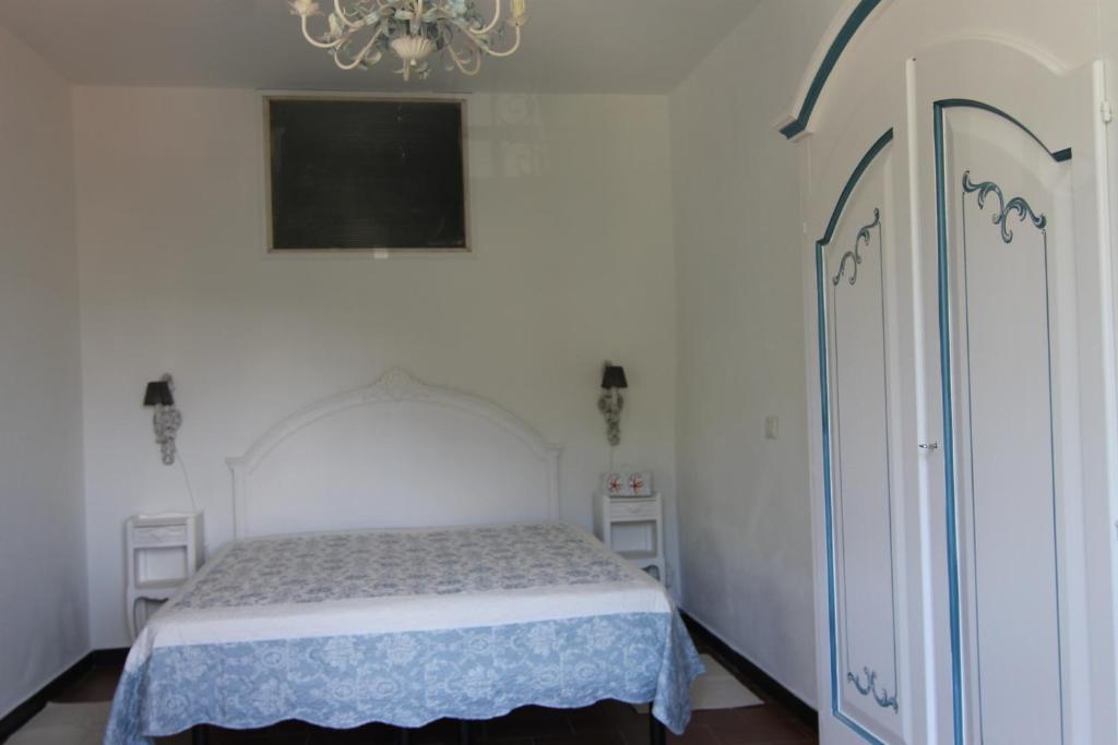 5 Lands Stone Cottage في ليفانتو: غرفة نوم بيضاء فيها سرير وثريا