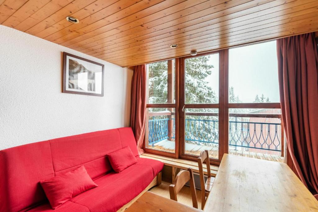 a living room with a red couch and a large window at Résidences quartier Charmettoger - maeva Home - Appartement duplex 3 pièces 6 in Arc 1800