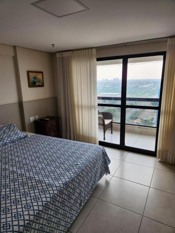 een slaapkamer met een bed en uitzicht op een balkon bij INOVA FLAT luxo no Condominio Cosmopolitan in Palmas