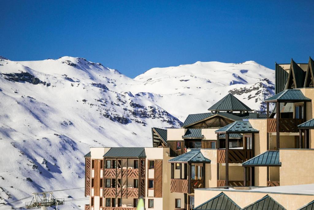 a building with snow covered mountains in the background at Résidence Les Temples du Soleil - maeva Home - 2 Pièces 5 Personnes Sélect 52 in Val Thorens