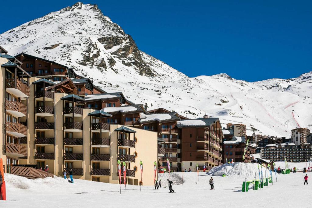 a building in the snow with a mountain in the background at Résidence Les Temples du Soleil - maeva Home - 2 Pièces 5 Personnes Sélect 52 in Val Thorens