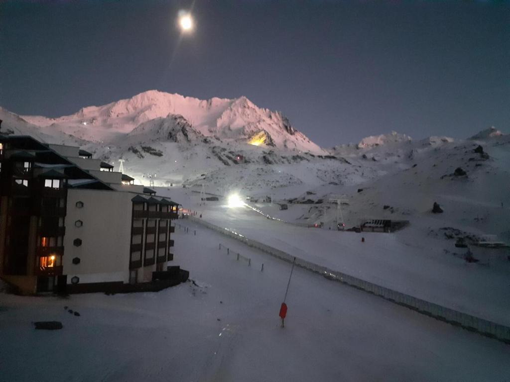 a person standing in the snow at night with a mountain at Résidence Les Temples du Soleil - maeva Home - 2 Pièces 5 Personnes Sélect 52 in Val Thorens