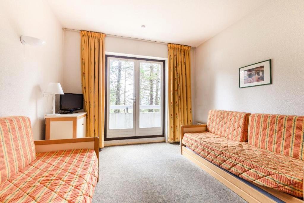 un salon avec un canapé et une fenêtre dans l'établissement Résidence L'Eyssina - maeva Home - Studio 5 Personnes Budget MAE-1940, à Vars