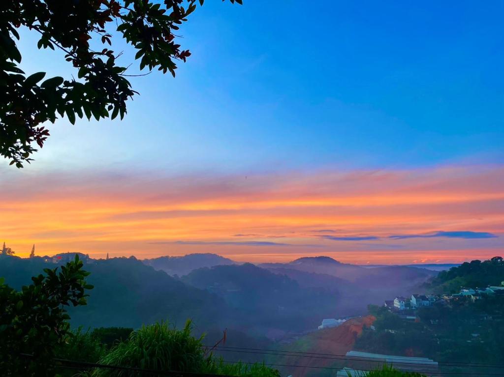 een uitzicht op de zonsondergang van een vallei met bergen bij Vân Các House in Xuan An