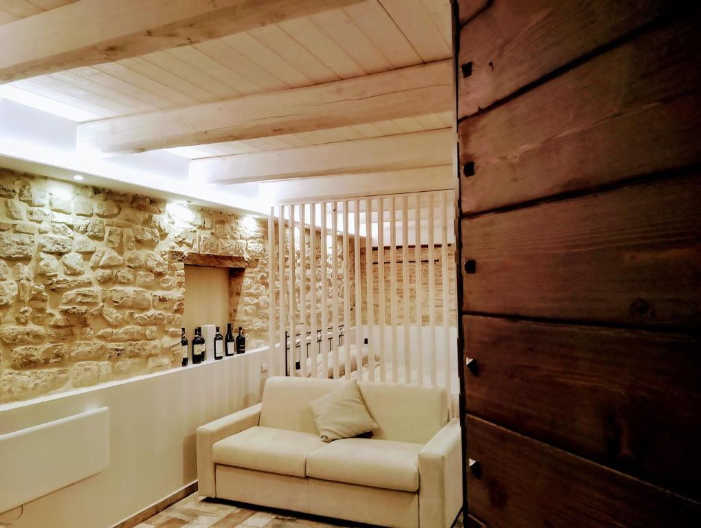 a living room with a white couch and a stone wall at Via Mazzini Home in Gubbio