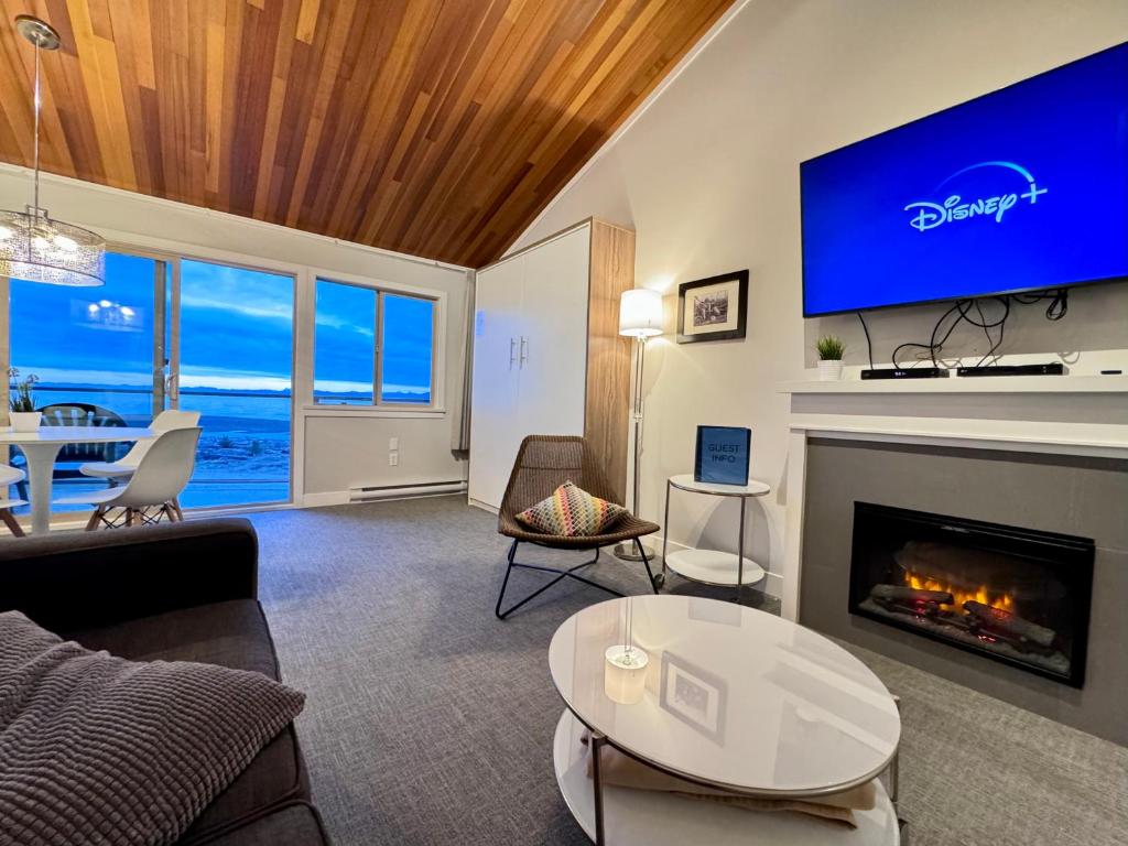 sala de estar con chimenea y TV en Oceanfront Loft - amazing views!, en Qualicum Beach