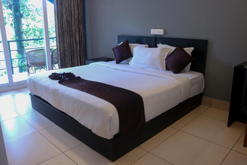 a large bed in a bedroom with a balcony at Edens Munnar in Munnar