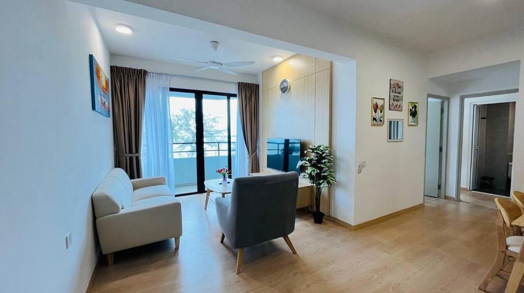 a living room with white furniture and a large window at Mutiara Melaka Beach Resort by Glex in Tangga Batu