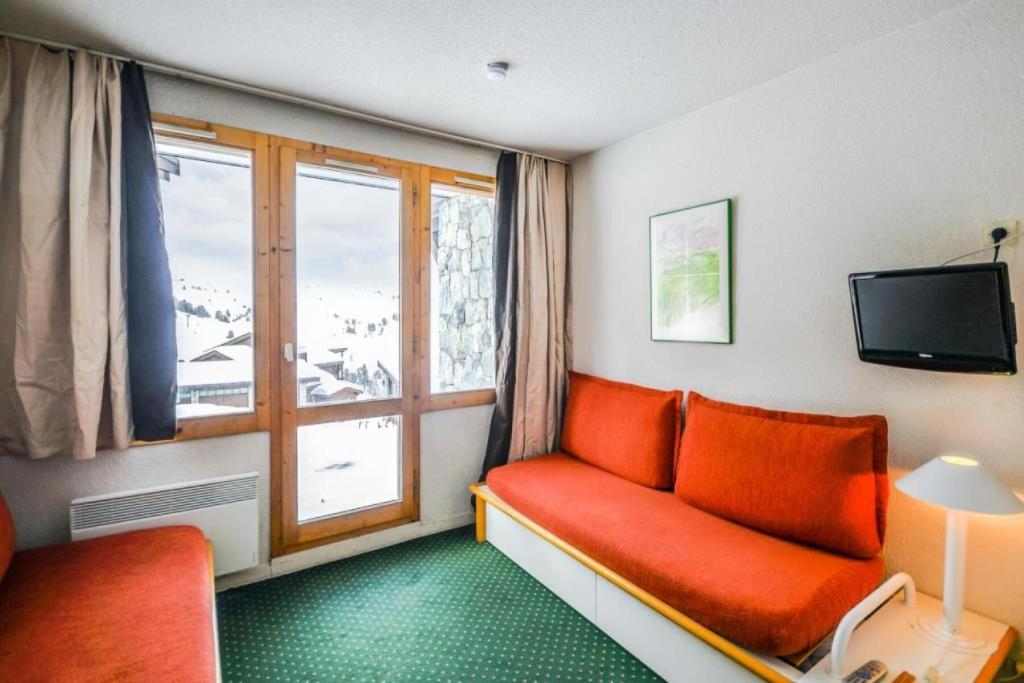 - un salon avec un canapé rouge et une fenêtre dans l'établissement Résidence Les Constellations - maeva Home - Studio 5 Personnes Confort MAE-5963, à La Plagne Tarentaise