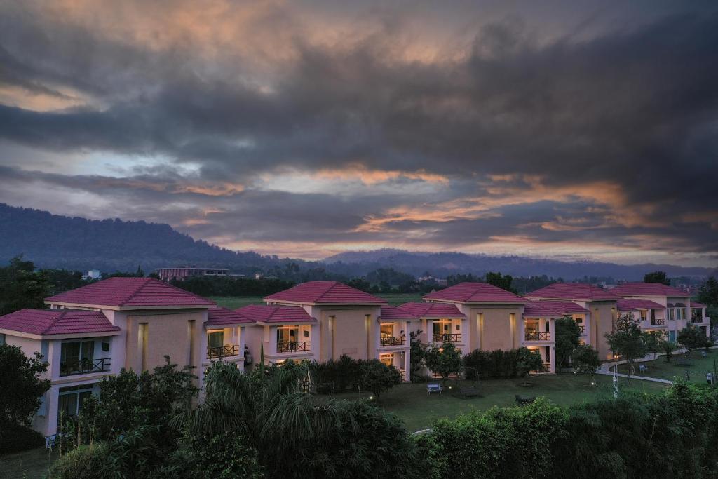 szereg domów z różowymi dachami pod pochmurnym niebem w obiekcie Resort De Coracao - Corbett , Uttarakhand w mieście Ramnagar