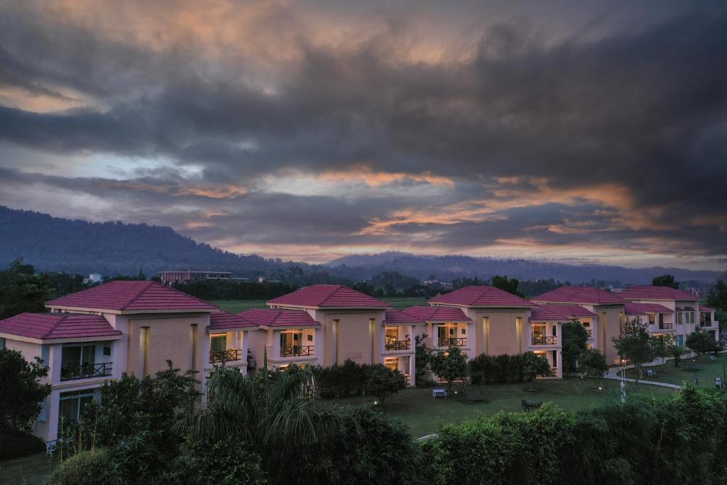 una fila di case con tetti rosa sotto un cielo nuvoloso di Resort De Coracao - Corbett , Uttarakhand a Ramnagar