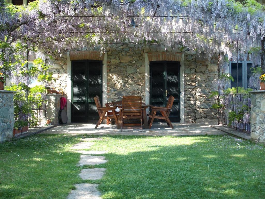 um pátio com uma mesa e cadeiras num quintal em Il Glicine em Zimone