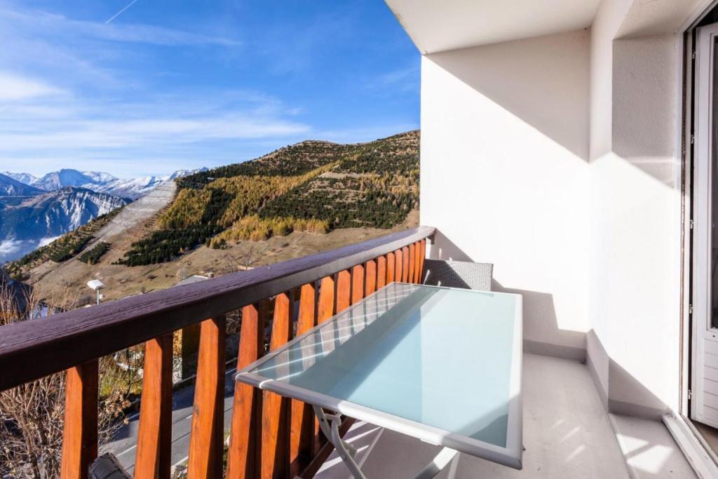 a glass table on a balcony with a view of mountains at Appartement 6 pers. à 30m des remontées - Maeva Particuliers - 3 Pièces 6 Personnes Sélection 138716 in L'Alpe-d'Huez