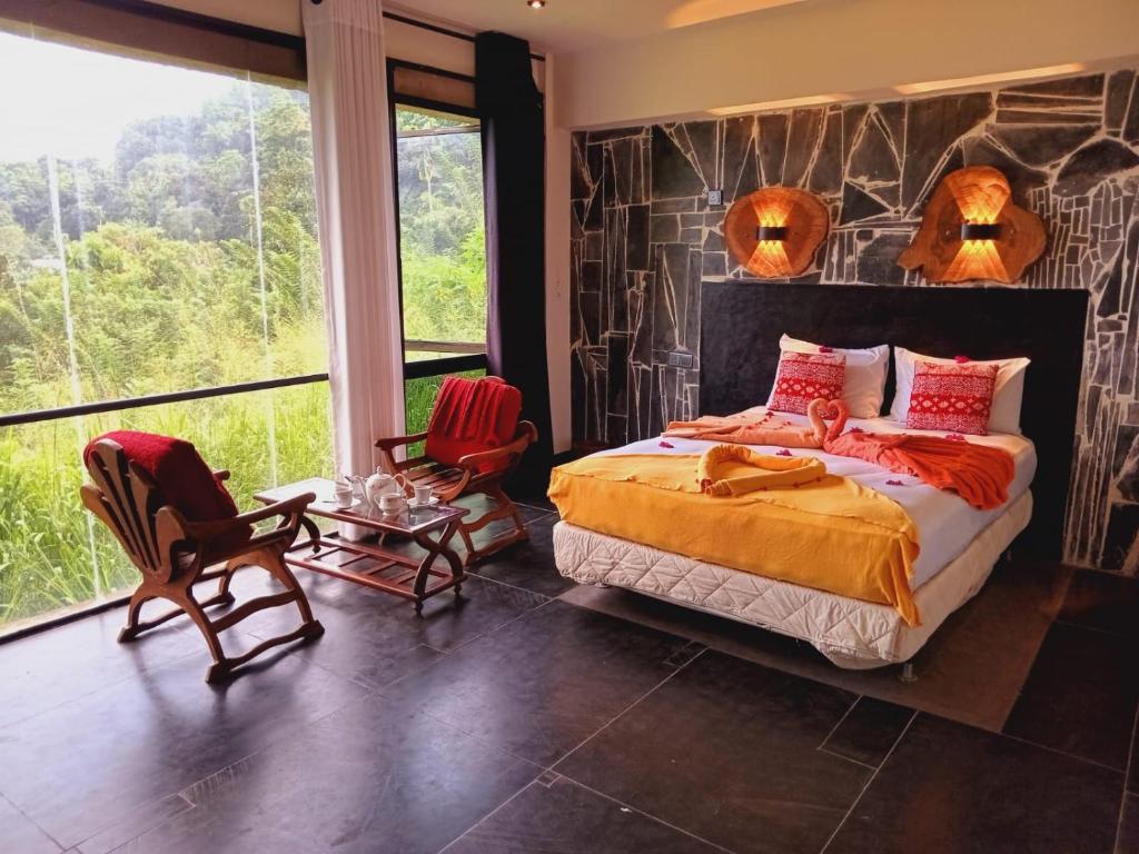 een slaapkamer met een groot bed en 2 stoelen bij Kandy IVY Mountain View Resort in Kandy