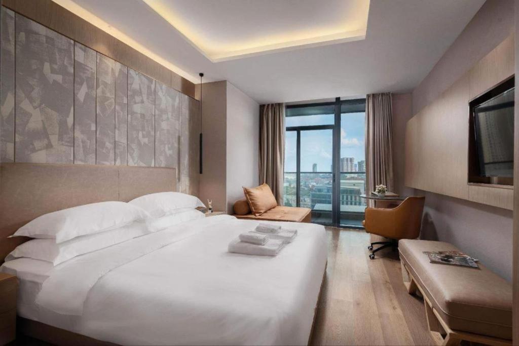 una habitación de hotel con una gran cama blanca y una ventana en SF HOTEL Penthouse Residences en Phnom Penh