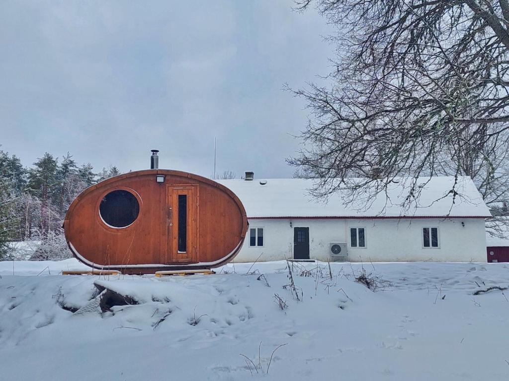 a large wooden oval building in the snow at Paganamaa puhkemaja ja peosaal in Liguri